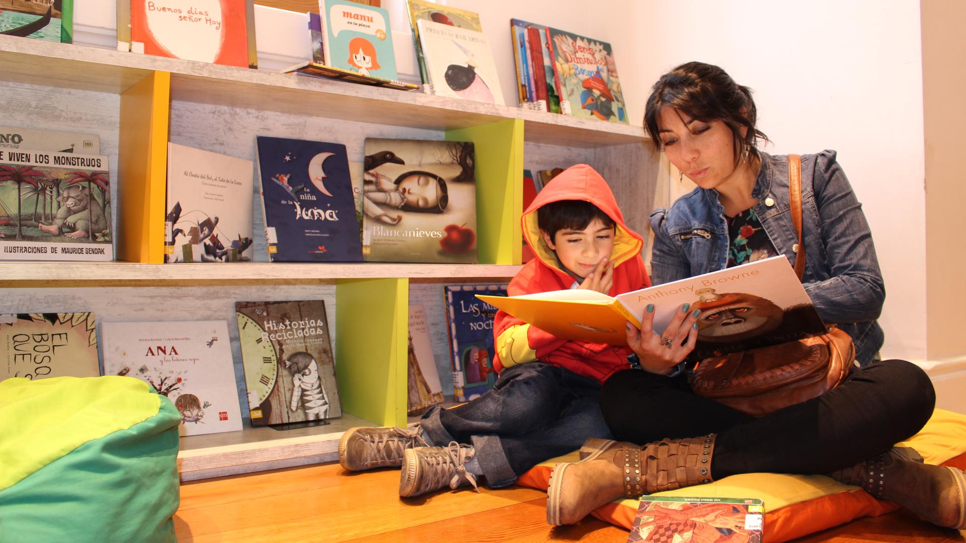 Madre leyendo cuento a hijo en la Sala Infantil de la biblioteca