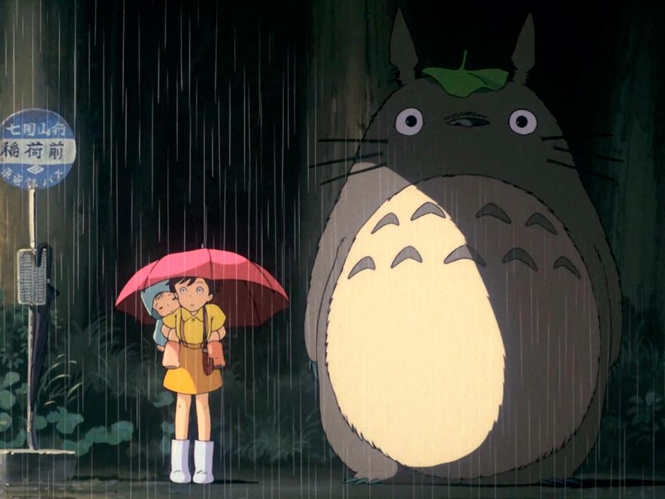 niña bajo paragua en la calle lloviendo junto a mono animado Totoro 