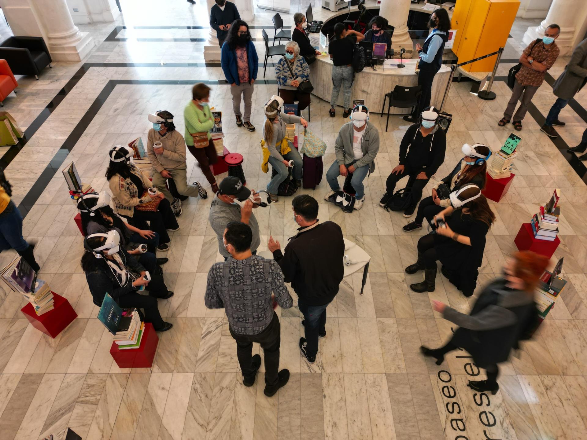 personas sentadas en el hall de la biblioteca con lentes de realidad virtual