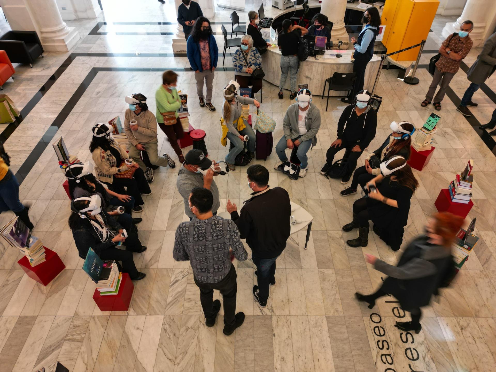 personas sentadas en el hall de la biblioteca con lentes de realidad virtual 