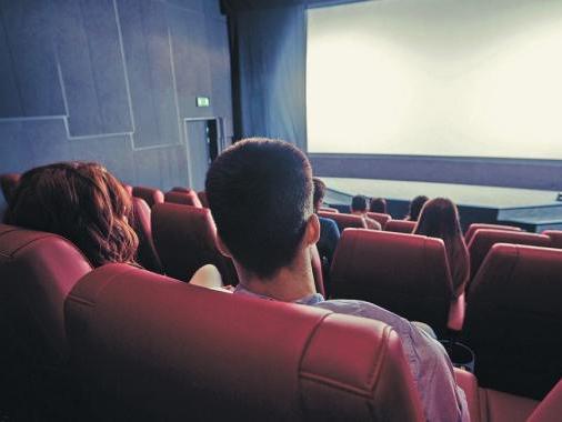 familia sentada en sala de cine esperando película 
