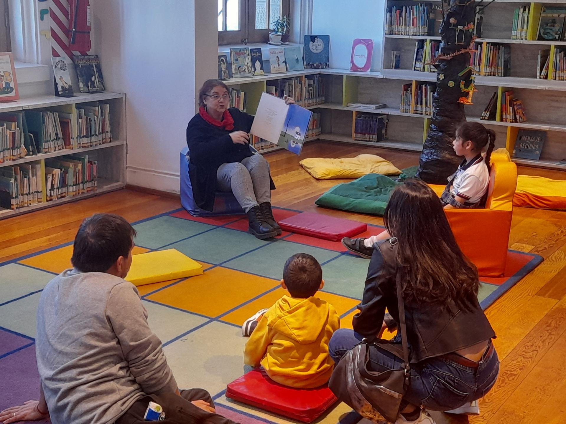 Grupo de niños y niñas junto a sus familias disfrutando de un cuenta cuentos en la biblioteca