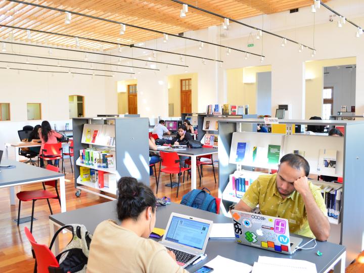 Usuarios y usuarias sentados en el tercer piso de la biblioteca