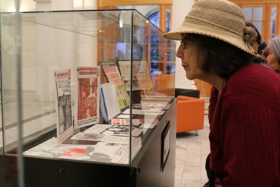 mujer mirando exposición que contiene diarios con información de detenidos desaparecidos 
