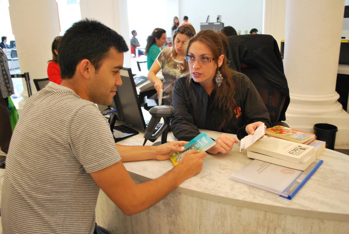 Funcionaria haciendo préstamo de libro a usuario